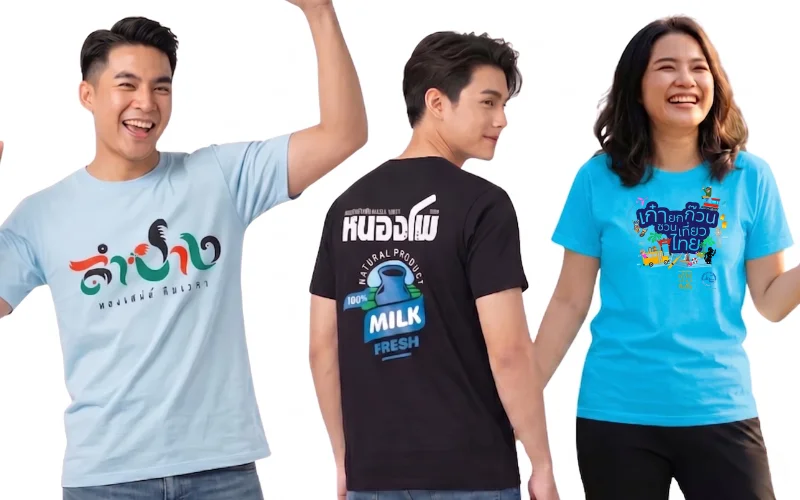 นายแบบและนางแบบสามคนสวมเสื้อยืดพิมพ์ลายกราฟิกสวยงามจากร้านสกรีนเสื้อ โดยคนซ้ายสุดสวมเสื้อยืดสีฟ้าอ่อนสกรีนลายข้อความภาษาไทย "ลำปาง หลงเสน่ห์ กาลเวลา" คนกลางหันหลังสวมเสื้อยืดสีดำสกรีนลายถังนม "หนองโพ MILK FRESH" และคนขวาสุดสวมเสื้อยืดสีฟ้าสดสกรีนลายการ์ตูนท่องเที่ยว "เก๋ายกก๊วน ชวนเที่ยวไทย" แสดงผลงานรับสกรีนเสื้อตามสั่ง ลายทั่วไป และลายลิมิเต็ดตามแบบที่ลูกค้าต้องการ บนพื้นหลังสีขาว